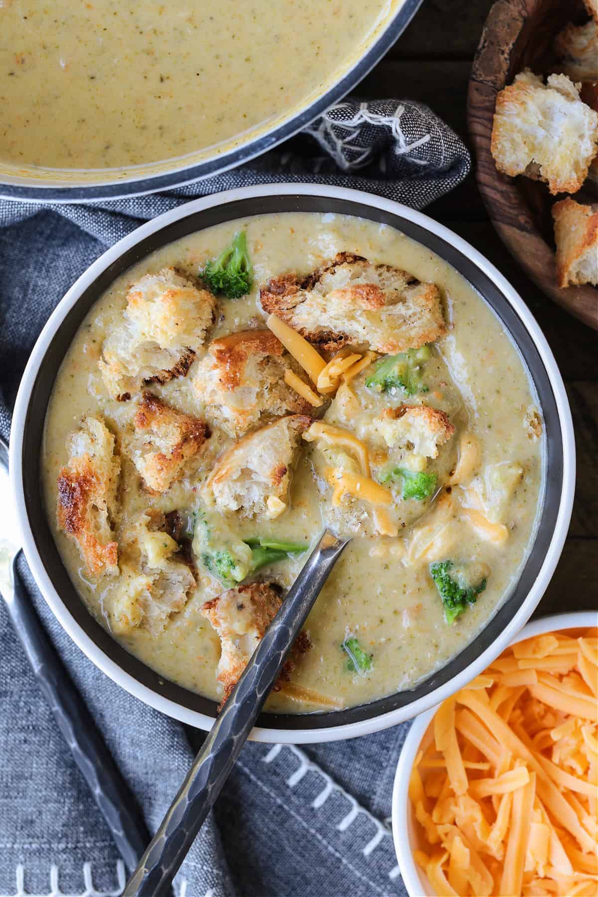 broccoli cheese soup in bowl with spoon and croutons