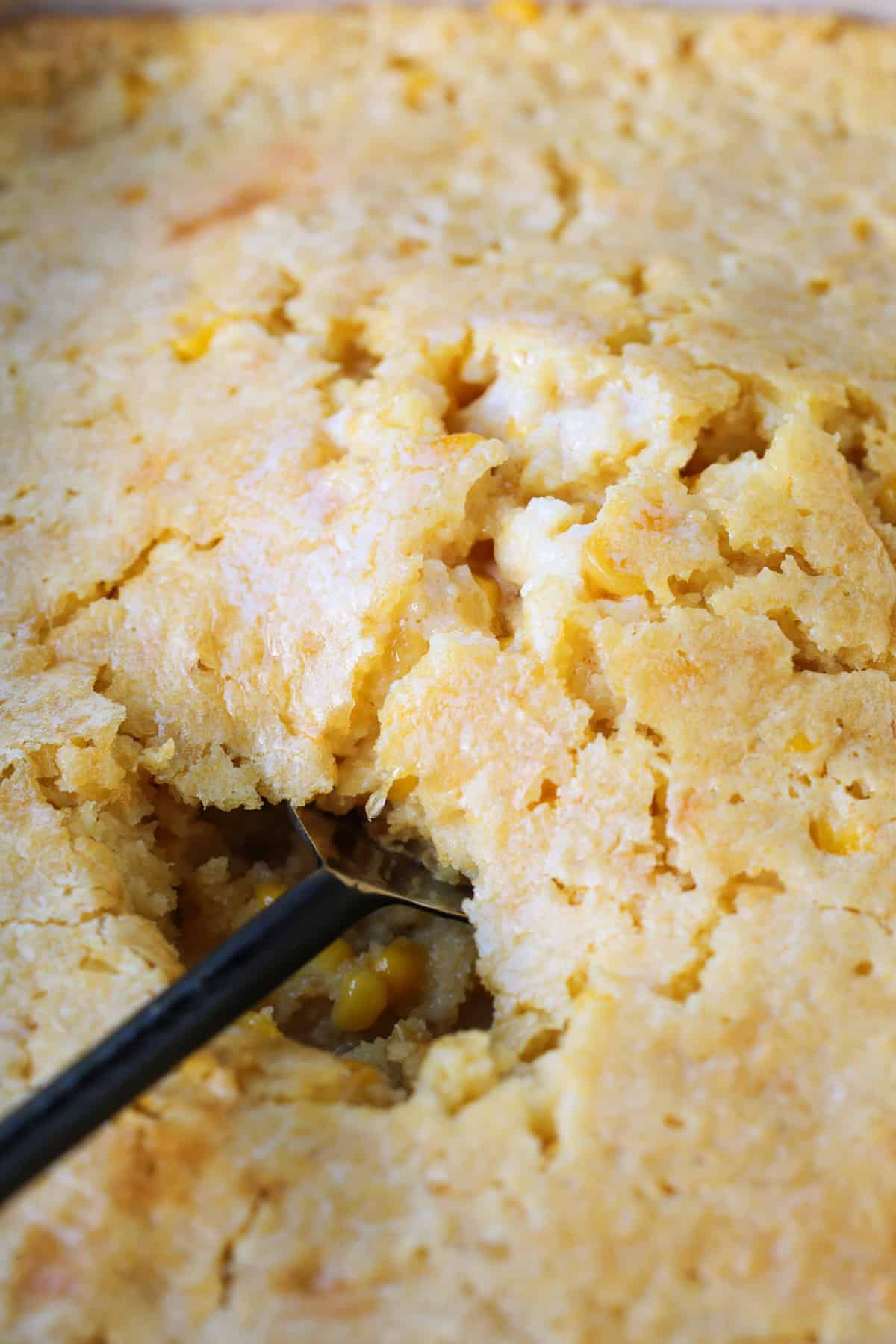 This creamy and sweet Corn Souffle is an delicious side dish for every occasion! Just 5 minutes of prep time and it's ready for the oven! corn souffle with a spoon in the middle
