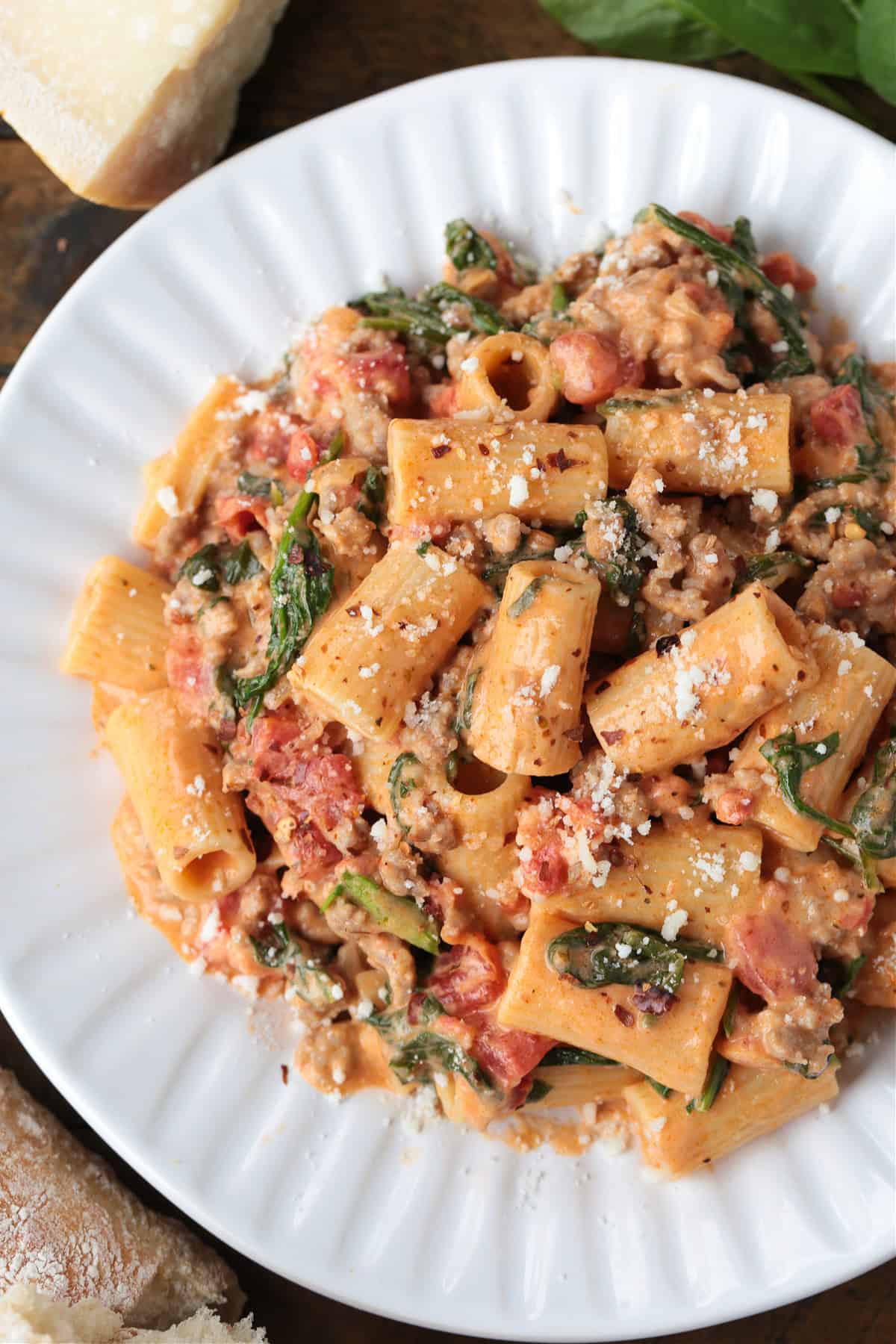 This creamy Pasta with Sausage and Spinach is sure to hit the spot! An easy to make pasta recipe that's ready to serve in just 30 minutes. rigatoni with sausage in a pink cream sauce on a white plate