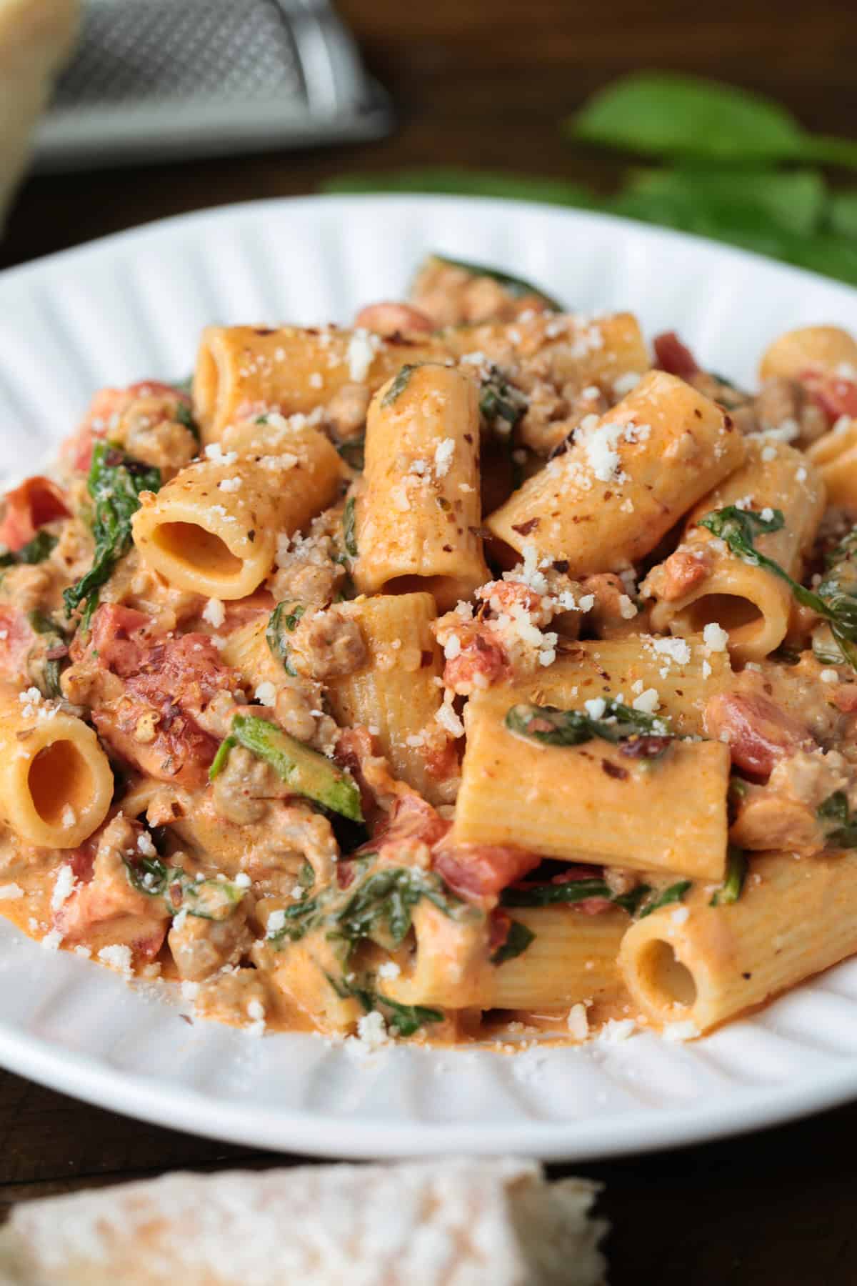 This creamy Pasta with Sausage and Spinach is sure to hit the spot! An easy to make pasta recipe that's ready to serve in just 30 minutes. rigatoni recipe in pink cream sauce on a white plate