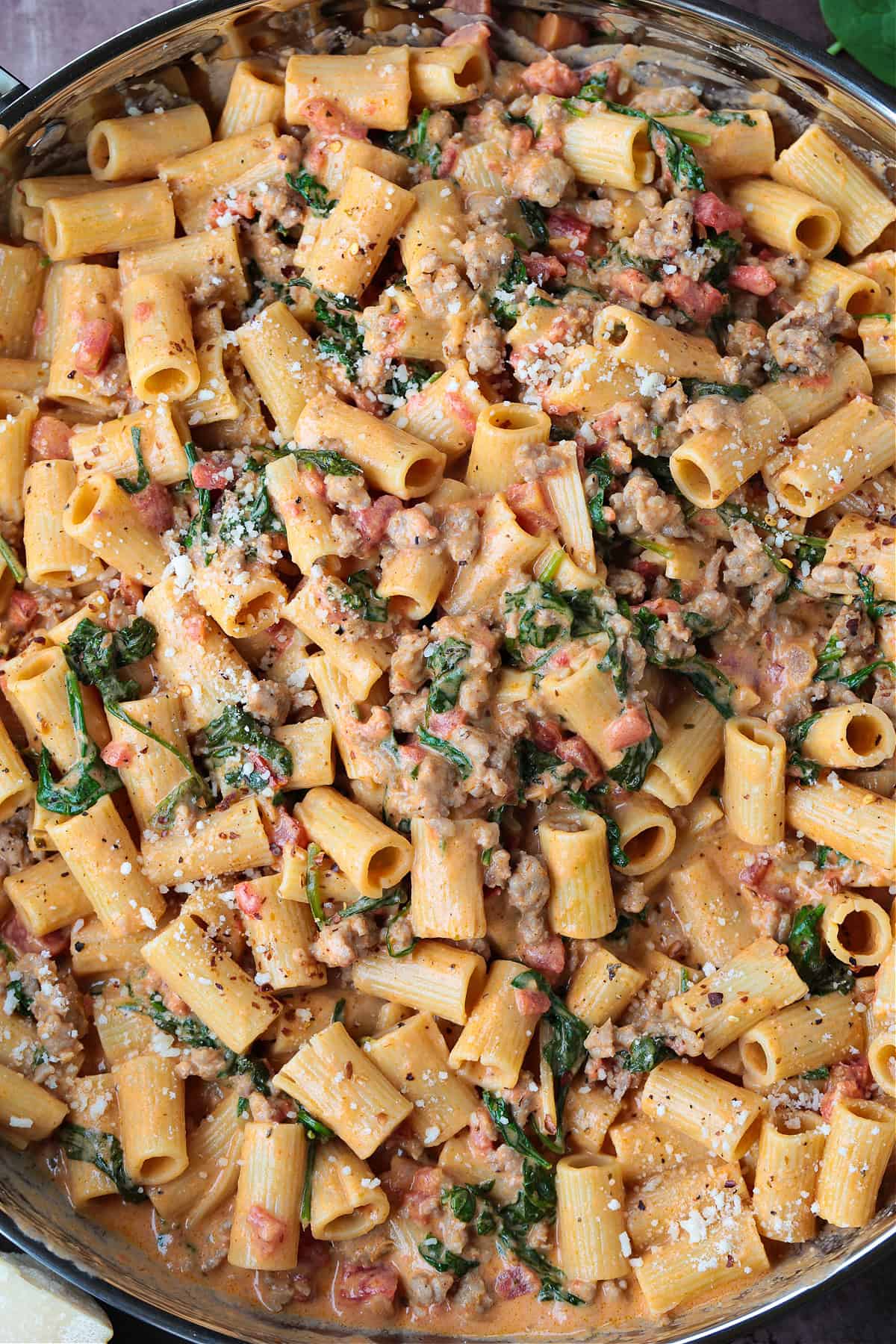 This creamy Pasta with Sausage and Spinach is sure to hit the spot! An easy to make pasta recipe that's ready to serve in just 30 minutes. rigatoni with sausage and spinach in a large skillet