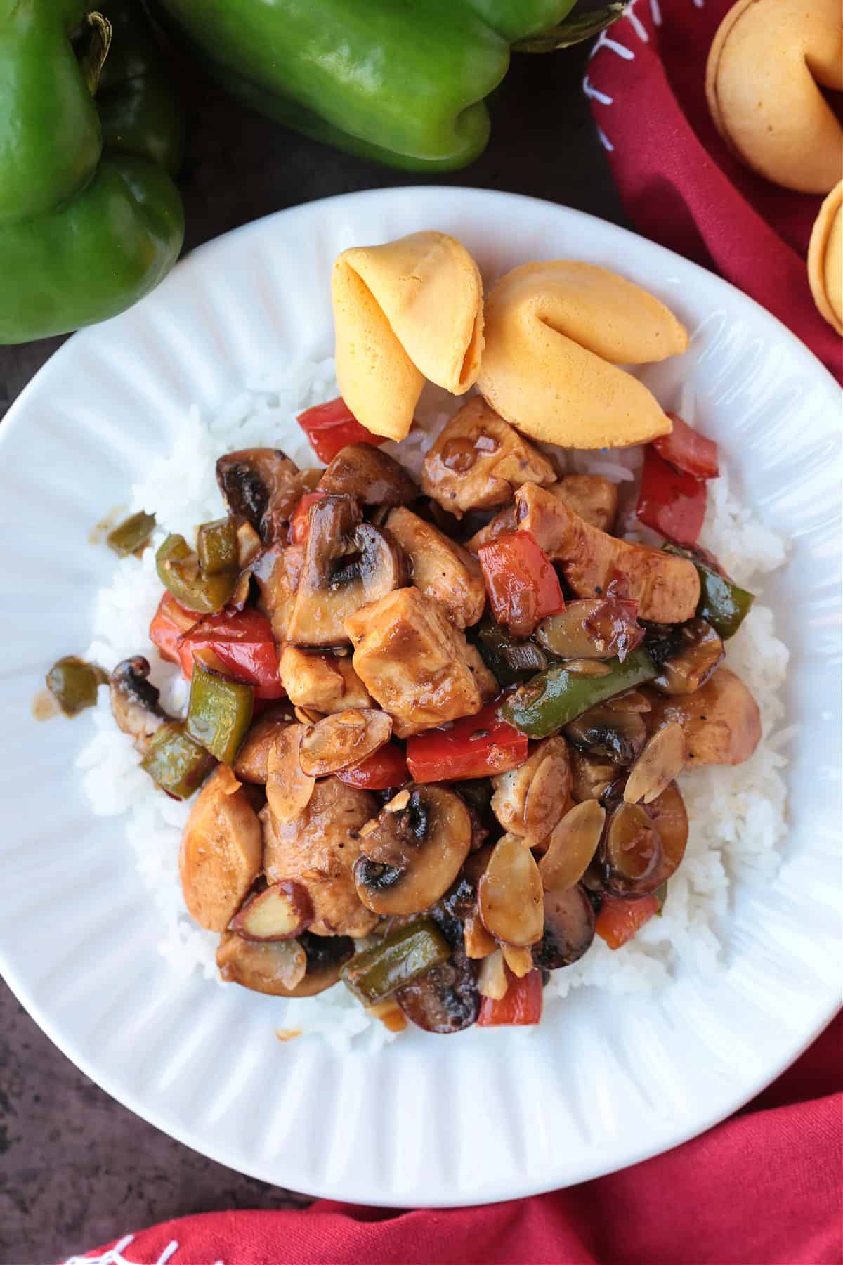 This Almond Chicken recipe is so easy to make and so delicious! Tossed with out homemade 5 minute stir fry sauce, it's better than take out! chicken stir fry with mushrooms, peppers and almonds on white plate