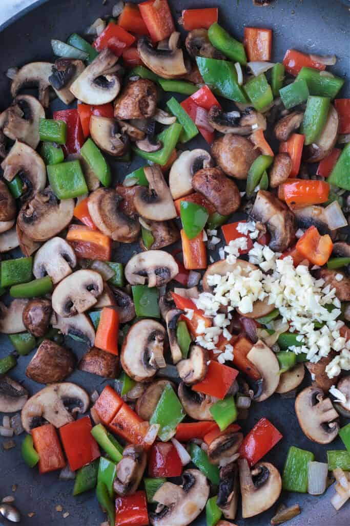 This Almond Chicken recipe is so easy to make and so delicious! Tossed with out homemade 5 minute stir fry sauce, it's better than take out! peppers, mushrooms and garlic in a skillet for making stir fry