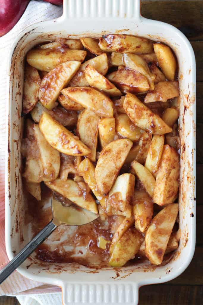 An easy, but dazzling dessert! Baked Sliced Apples are so delicious spooned over ice cream or served with whipped cream on the side. baked apples in baking dish with spoon
