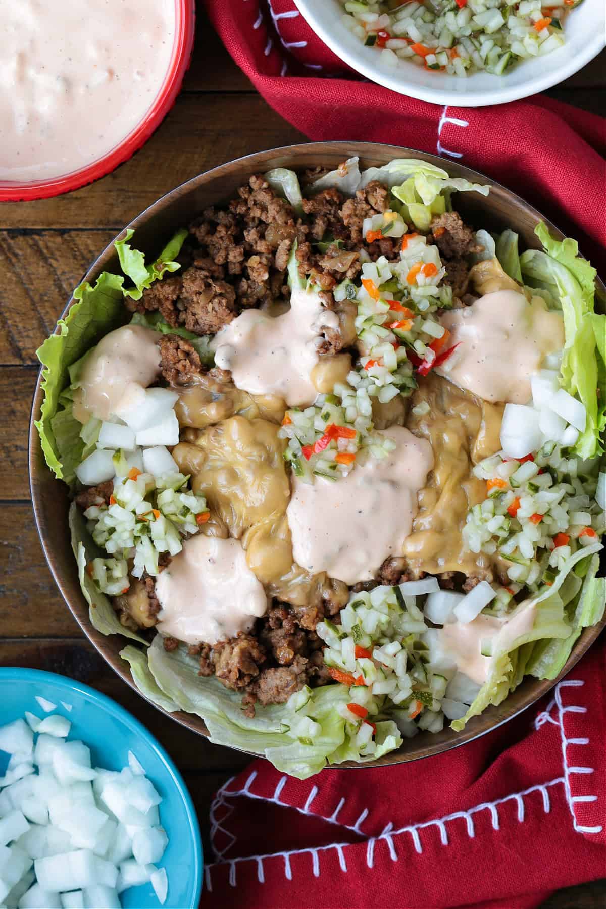 Make a Cheeseburger Bowl for parties, game days or just a fun dinner! All the flavors of your favorite cheeseburger drizzled with mac sauce! cheeseburger bowl with napkin and toppings on the side