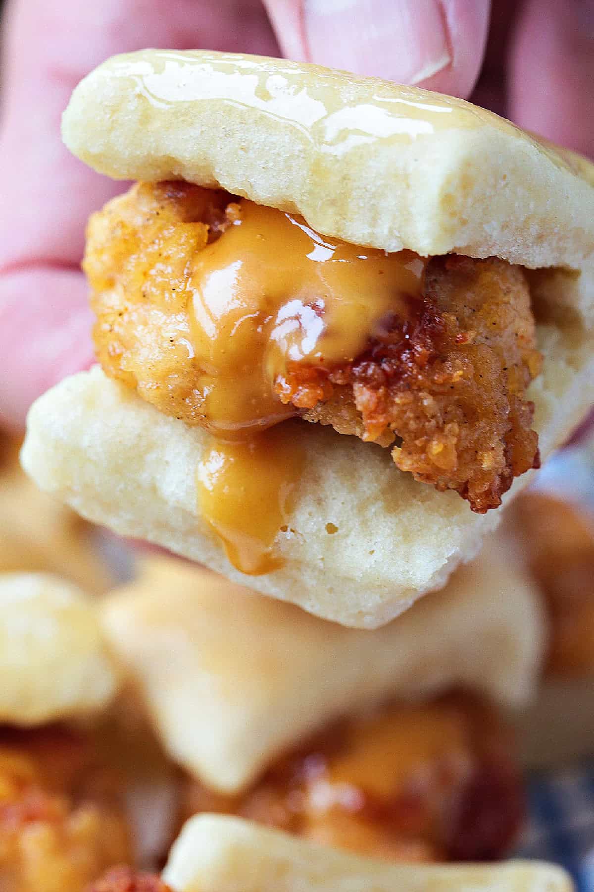 Make these Copycat Chicken Minis for your next party or game day! Just like the Chick Fil A version only better because they're homemade! hand holding mini chicken slider with sauce