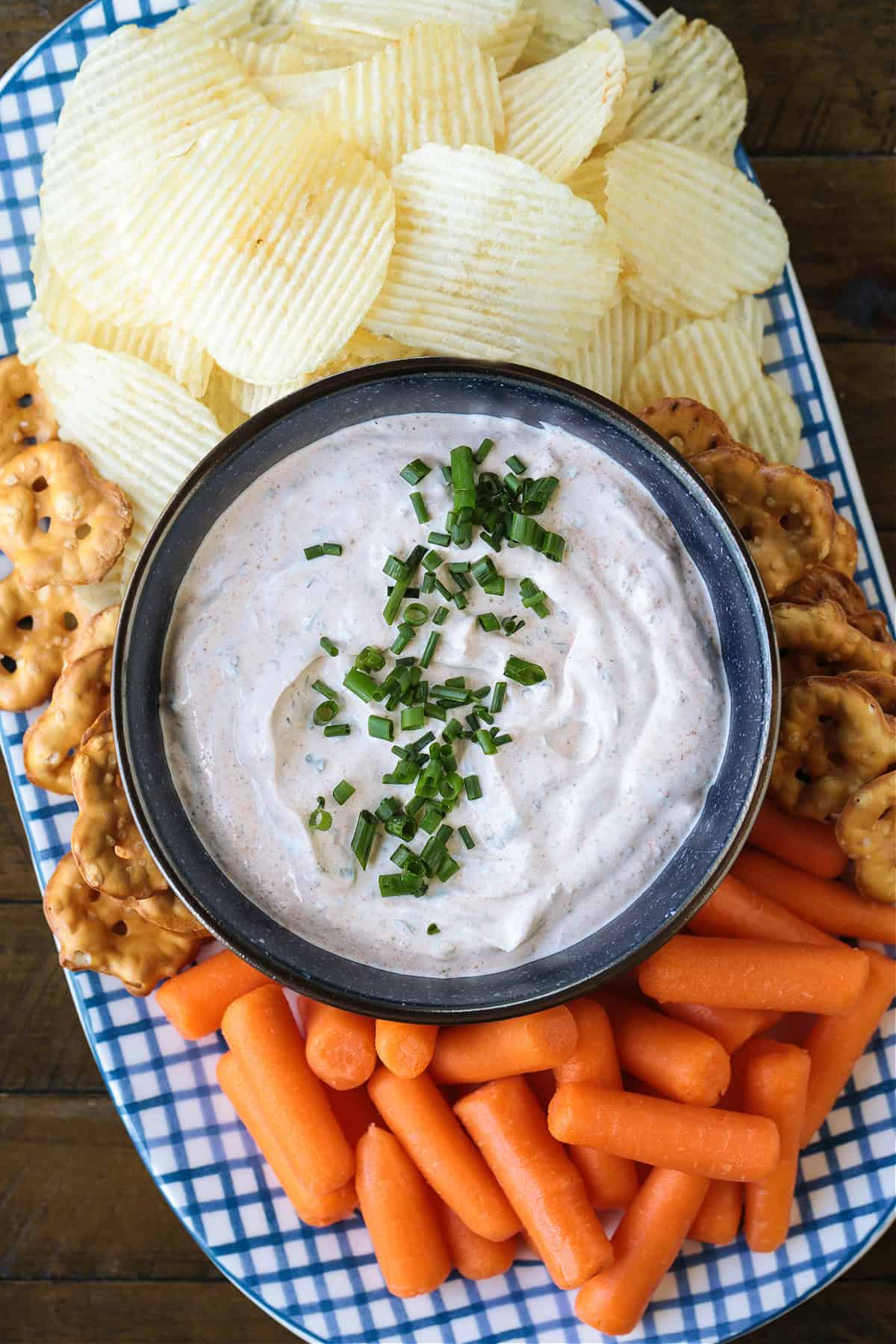 This Sour Cream Dip is a party appetizer staple! Perfect for dipping chips, pretzels and veggies, everyone will be asking for the recipe! bowl of dip on a platter with chips and carrots