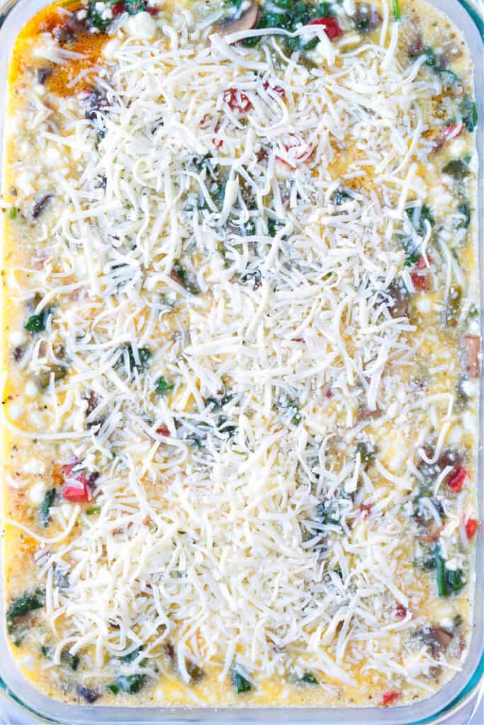 This Italian Breakfast Casserole is delicious for brunch or dinner with a salad! We love this cozy and hearty casserole any time of the day! baking dish with uncooked egg casserole, topped with cheese