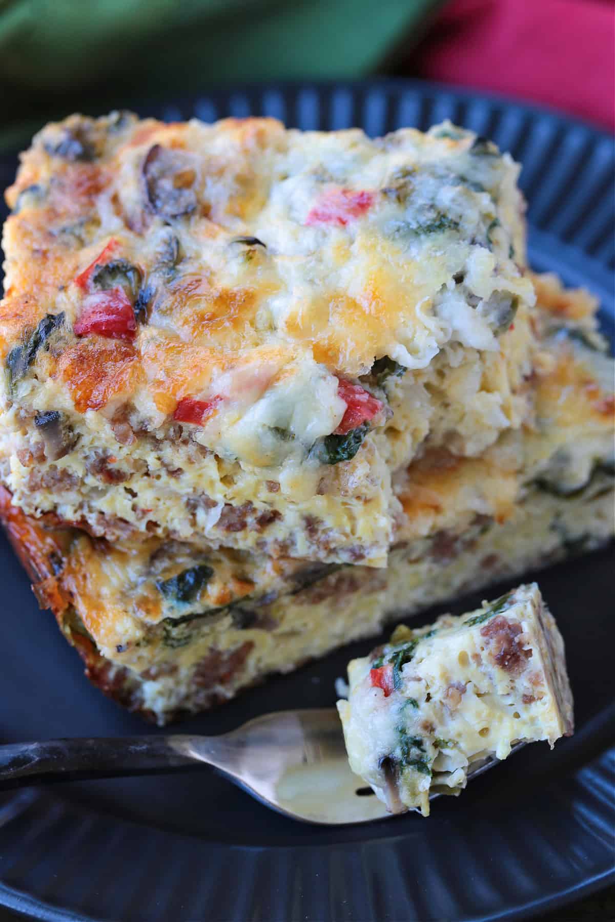 This Italian Breakfast Casserole is delicious for brunch or dinner with a salad! We love this cozy and hearty casserole any time of the day! egg bake on black plate with bite on fork