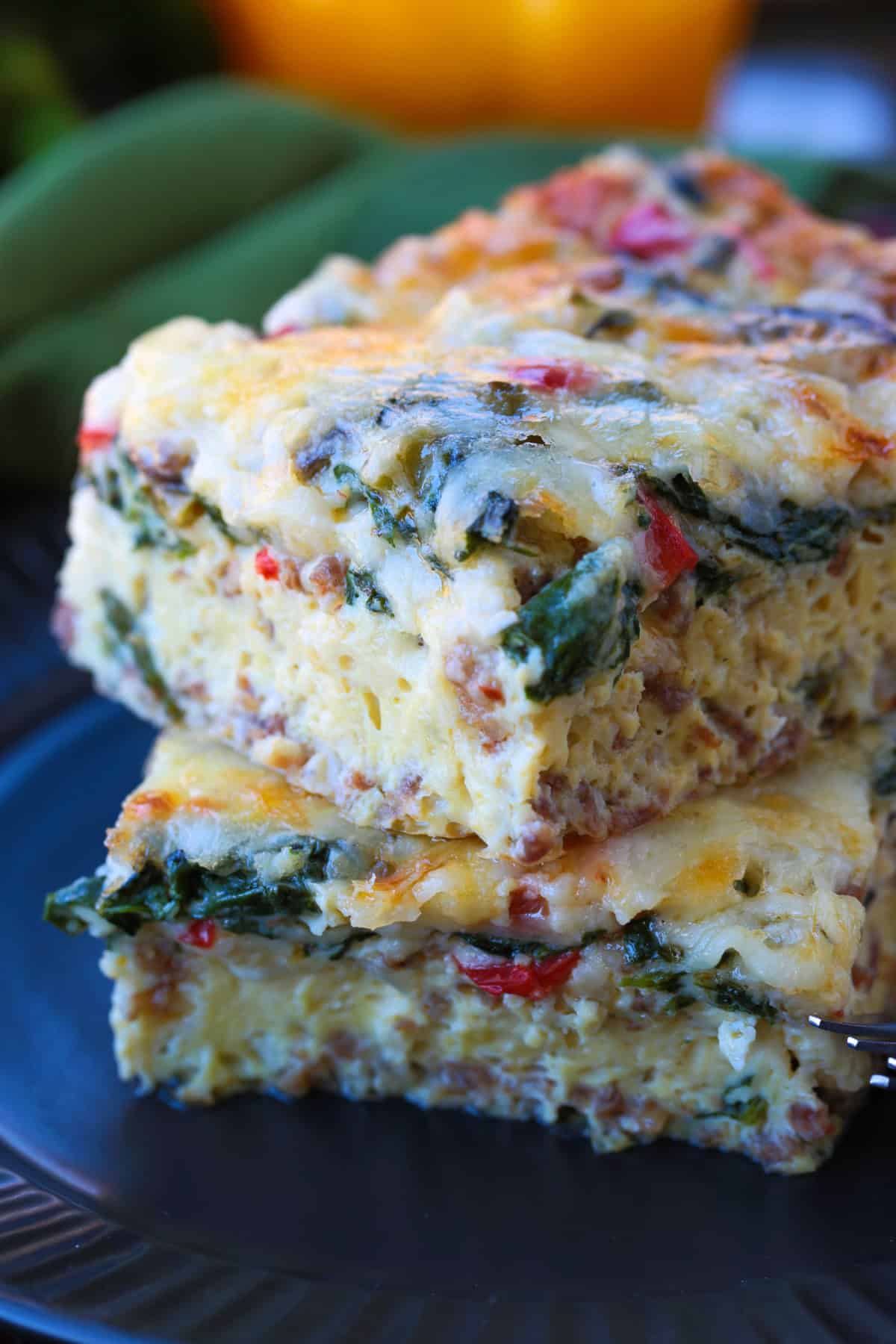 This Italian Breakfast Casserole is delicious for brunch or dinner with a salad! We love this cozy and hearty casserole any time of the day! squares of egg casserole stacked on plate