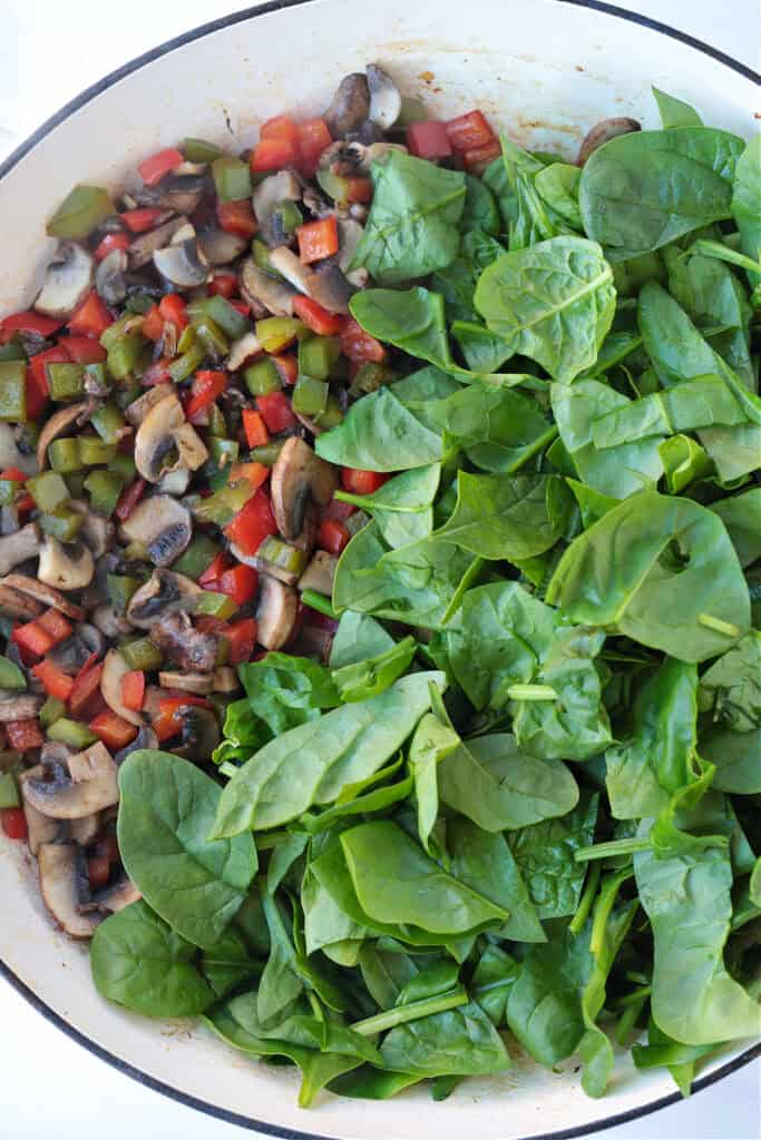 This Italian Breakfast Casserole is delicious for brunch or dinner with a salad! We love this cozy and hearty casserole any time of the day! cooked vegetables in skillet with fresh spinach
