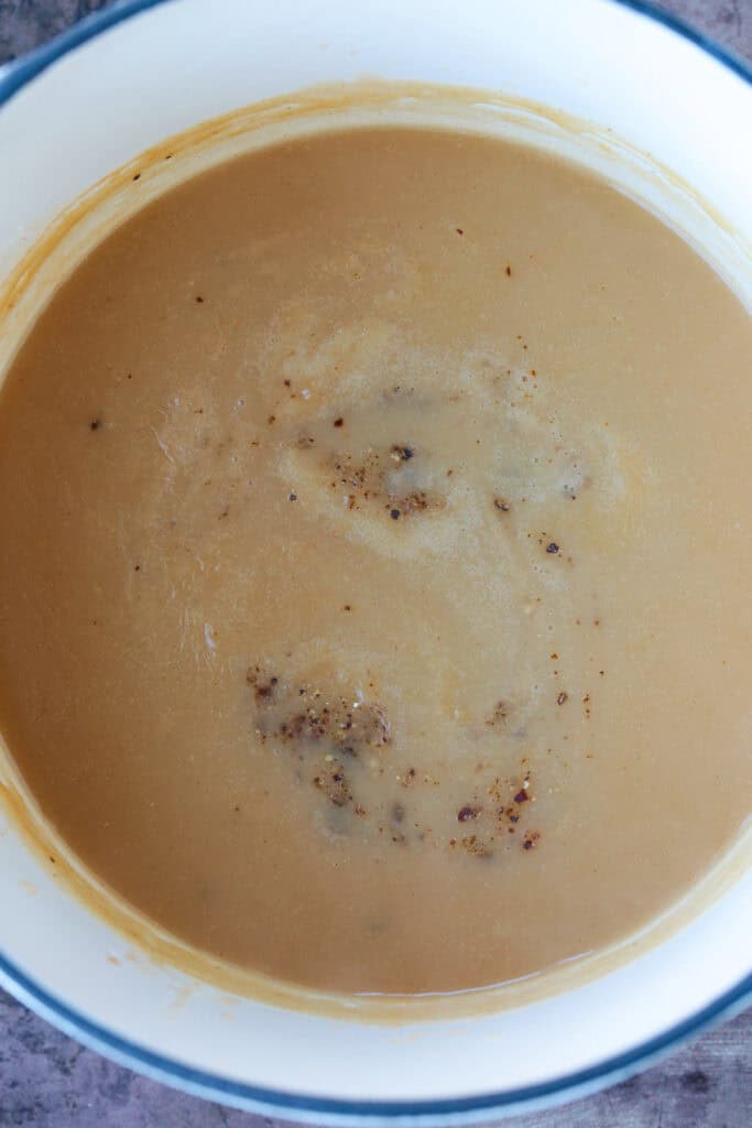 This homemade turkey gravy from drippings only takes minutes to make! A creamy, thick, delicious gravy recipe for your entire turkey dinner! gravy in pot with seasonings