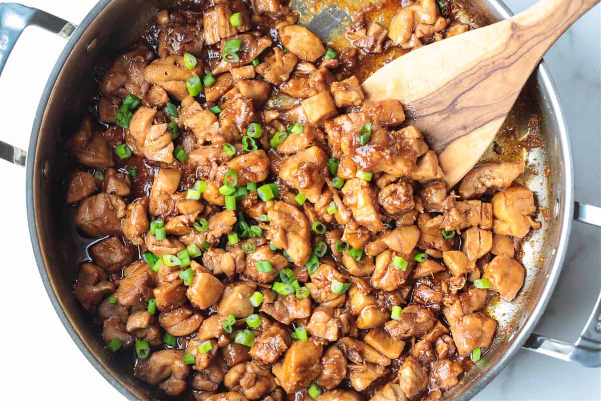 Our Easy Bourbon Chicken is a family favorite dinner recipe! Tender chicken in a sweet and tangy sauce with just a splash of bourbon. bourbon chicken in a skillet with spatula
