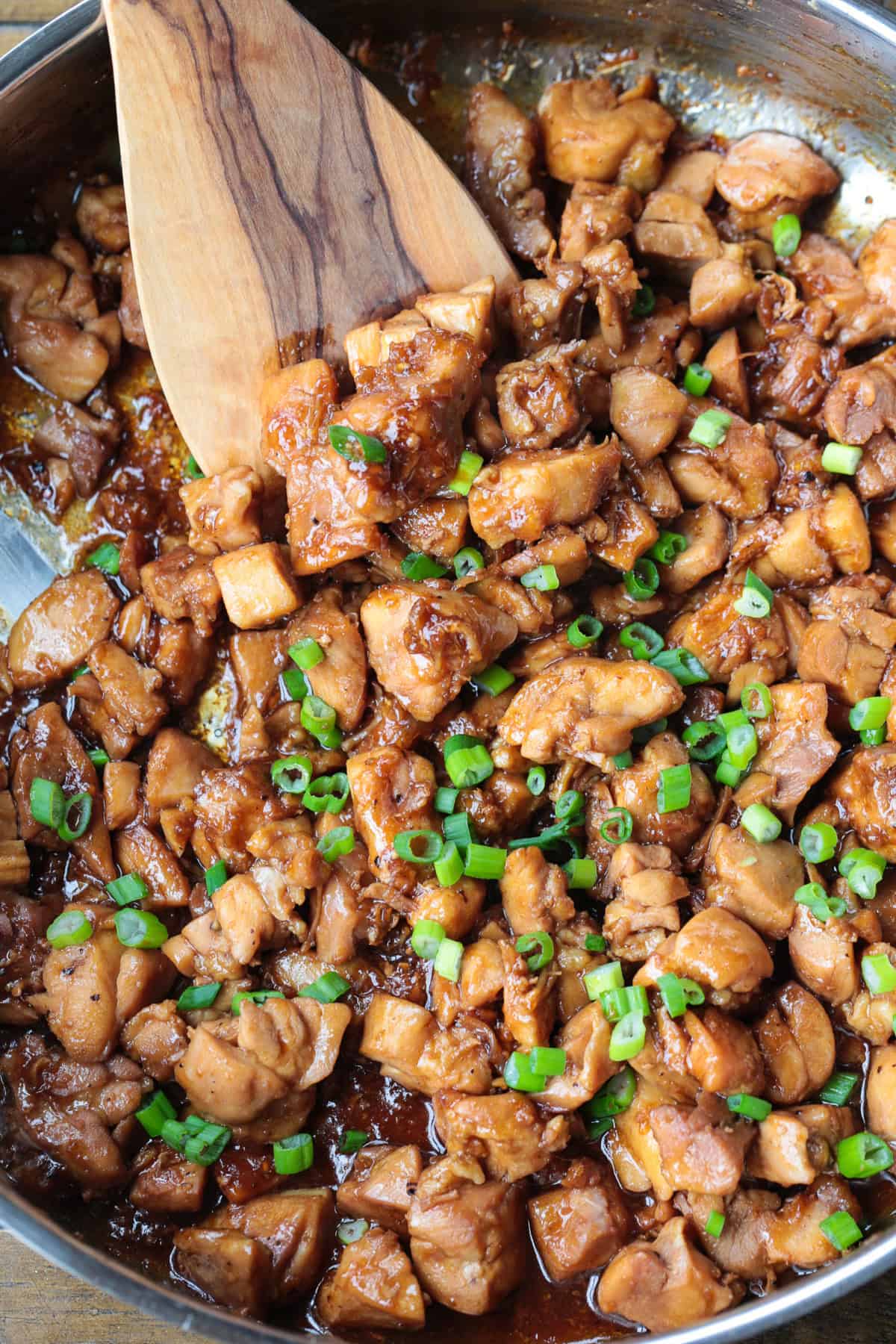 Our Easy Bourbon Chicken is a family favorite dinner recipe! Tender chicken in a sweet and tangy sauce with just a splash of bourbon. bourbon chicken in a skillet with wooden spatula