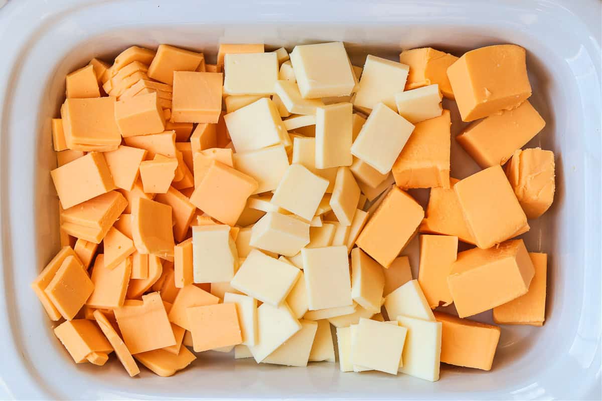Slow Cooker Queso is going to be the center of attention at any party or game day! Use it as a dip, drizzle on nachos or use in burritos! slow cooker with cubed cheeses