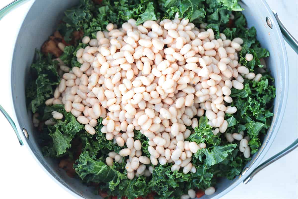 Flavorful White Bean and Sausage Soup is so hearty and nourishing. Tender white beans, kale and chicken sausage with a touch if white wine. white beans and kale in a pot for soup recipe