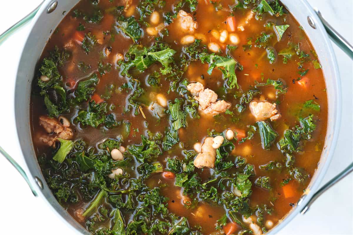Flavorful White Bean and Sausage Soup is so hearty and nourishing. Tender white beans, kale and chicken sausage with a touch if white wine. soup with kale and white beans in a pot