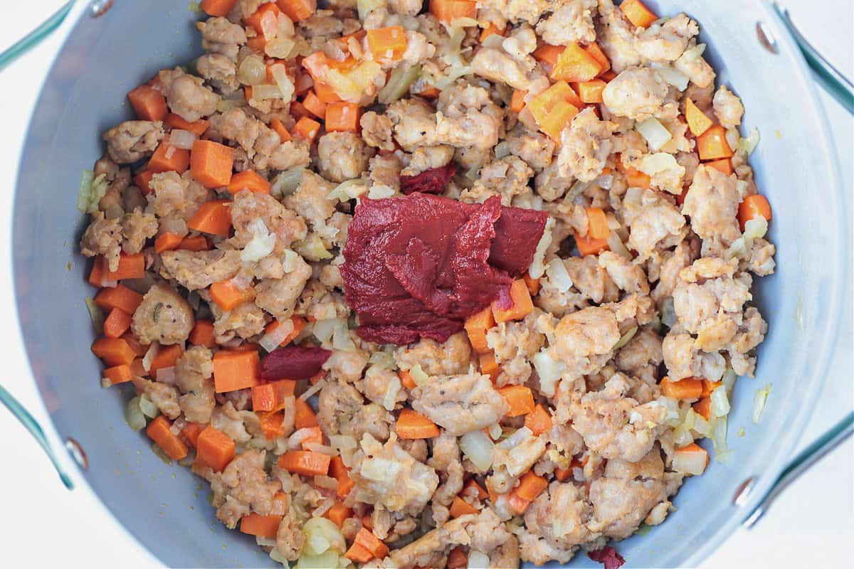 Flavorful White Bean and Sausage Soup is so hearty and nourishing. Tender white beans, kale and chicken sausage with a touch if white wine. sausage and vegetables in a pot with tomato paste