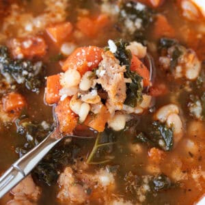 soup with vegetables and sausage on a spoon in a bowl