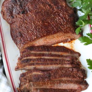 flank steak sliced on platter with parsley