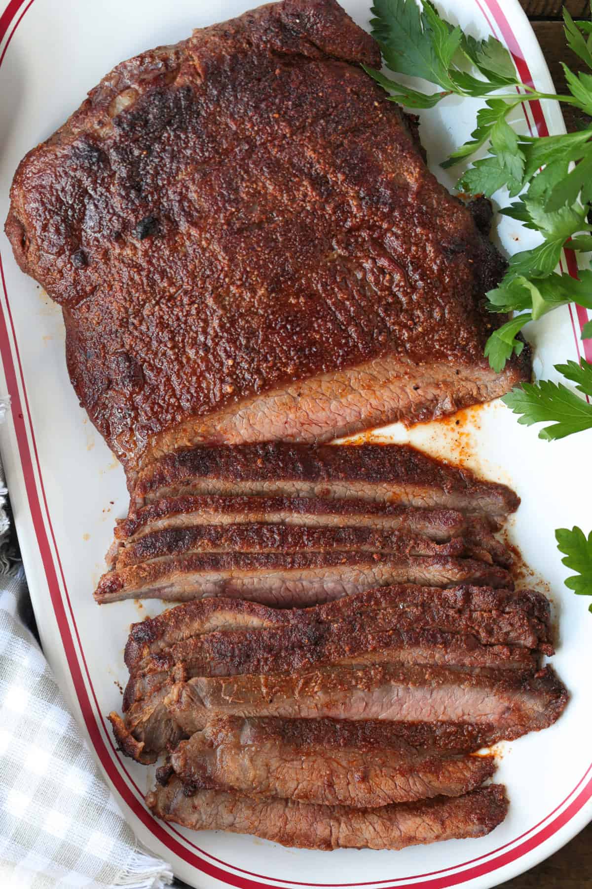 Need dinner fast? Our Air Fryer Flank Steak recipe delivers a tender, juicy, and flavorful steak with a crispy sear in just minutes! flank steak sliced on platter with parsley