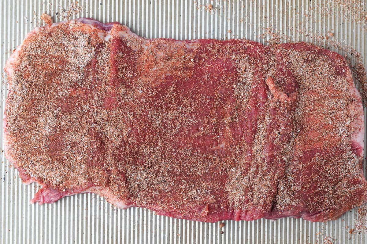 Need dinner fast? Our Air Fryer Flank Steak recipe delivers a tender, juicy, and flavorful steak with a crispy sear in just minutes! seasoned steak on a sheet pan