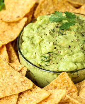 guacamole in glass bowl garnished with pepper and cilantro