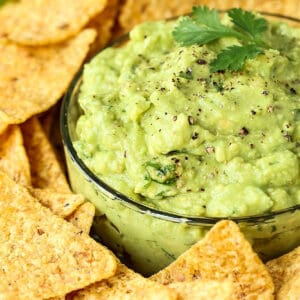 guacamole in glass bowl garnished with pepper and cilantro