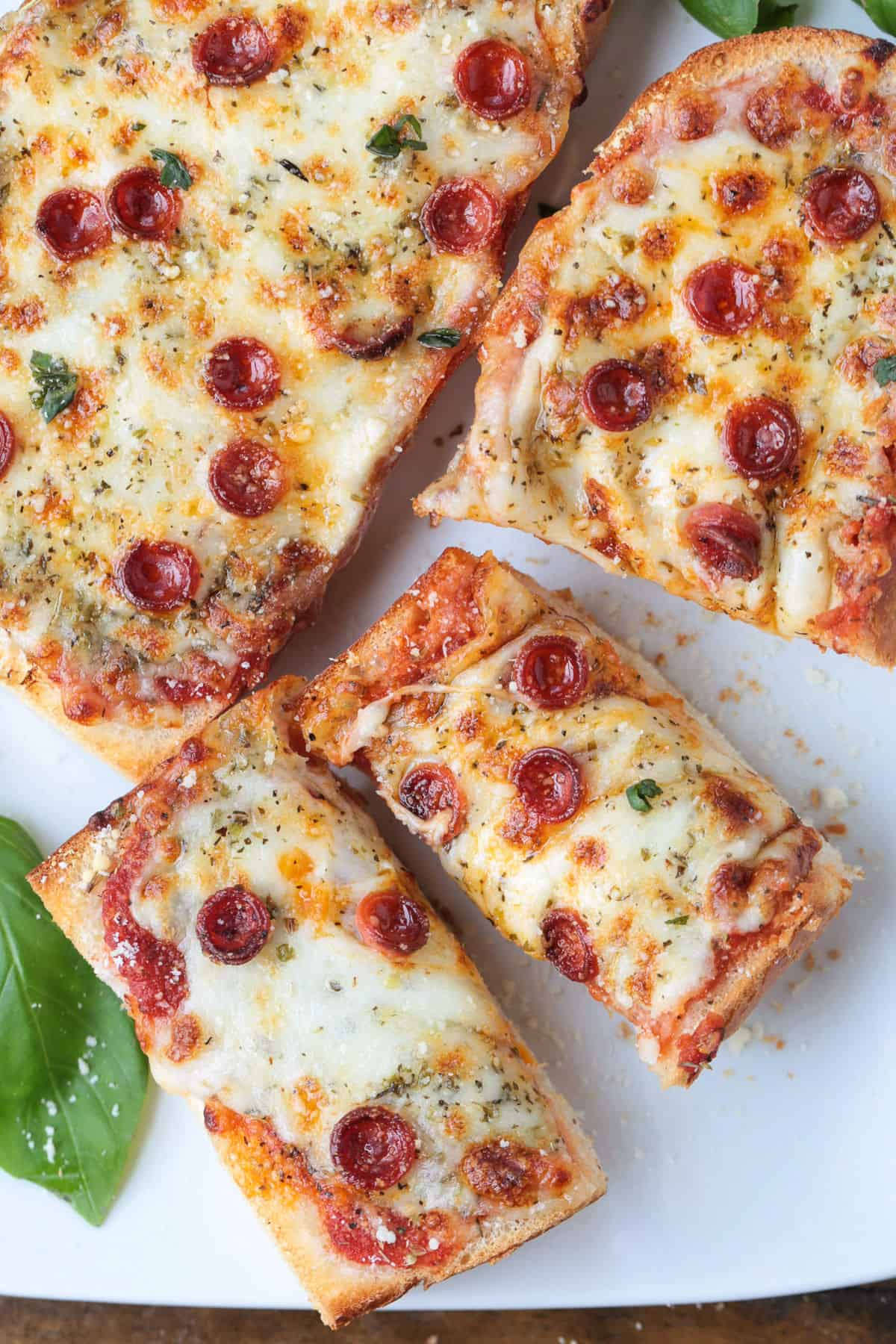 This Air Fryer French Bread Pizza is crispy, cheesy perfection! Ready in minutes, it’s an easy weeknight dinner, quick lunch or snack. french bread pizza sliced on a white platter