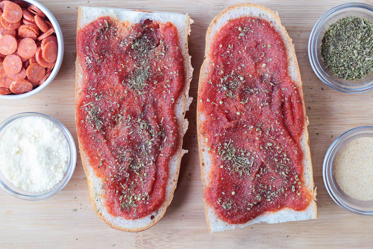 This Air Fryer French Bread Pizza is crispy, cheesy perfection! Ready in minutes, it’s an easy weeknight dinner, quick lunch or snack. pizza sauce on french bread with seasonings