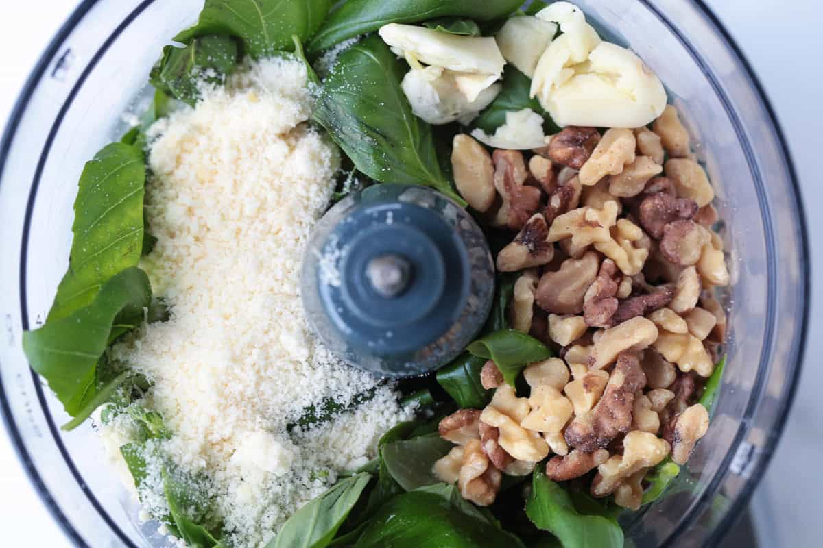 Make this tasty basil walnut pesto with just a few simple ingredients. A quick, vibrant sauce for chicken, fish or steak and so much more! ingredients for making pesto in a food processor