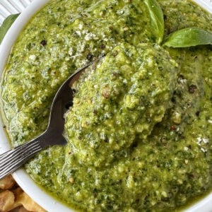 basil walnut pesto in a white bowl with spoon