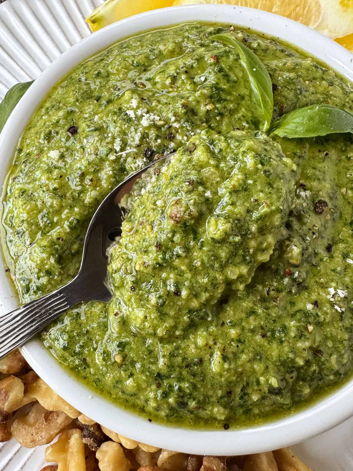 Make this tasty basil walnut pesto with just a few simple ingredients. A quick, vibrant sauce for chicken, fish or steak and so much more! basil walnut pesto in a white bowl with spoon