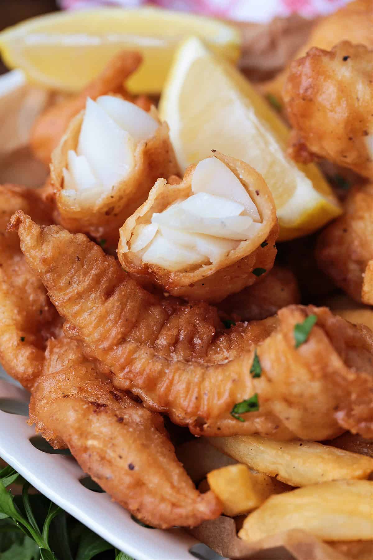 Make crispy, golden beer battered cod at home with our easy recipe! Flaky cod coated in a light beer batter and fried to a crispy perfection. piece of fried cod broken in half