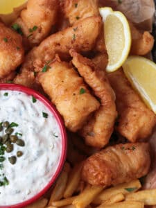 fried cod on a platter with lemon and tartar sauce