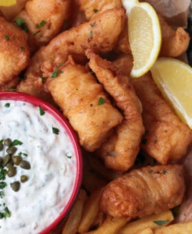 fried cod on a platter with lemon and tartar sauce