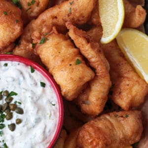 fried cod on a platter with lemon and tartar sauce