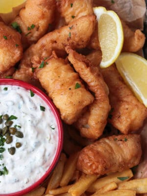 fried cod on a platter with lemon and tartar sauce
