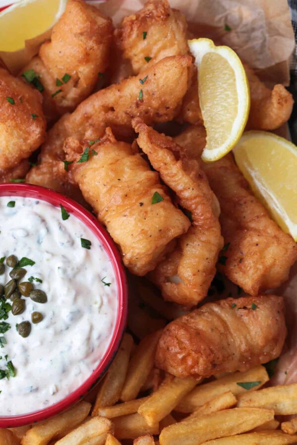 fried cod on a platter with lemon and tartar sauce