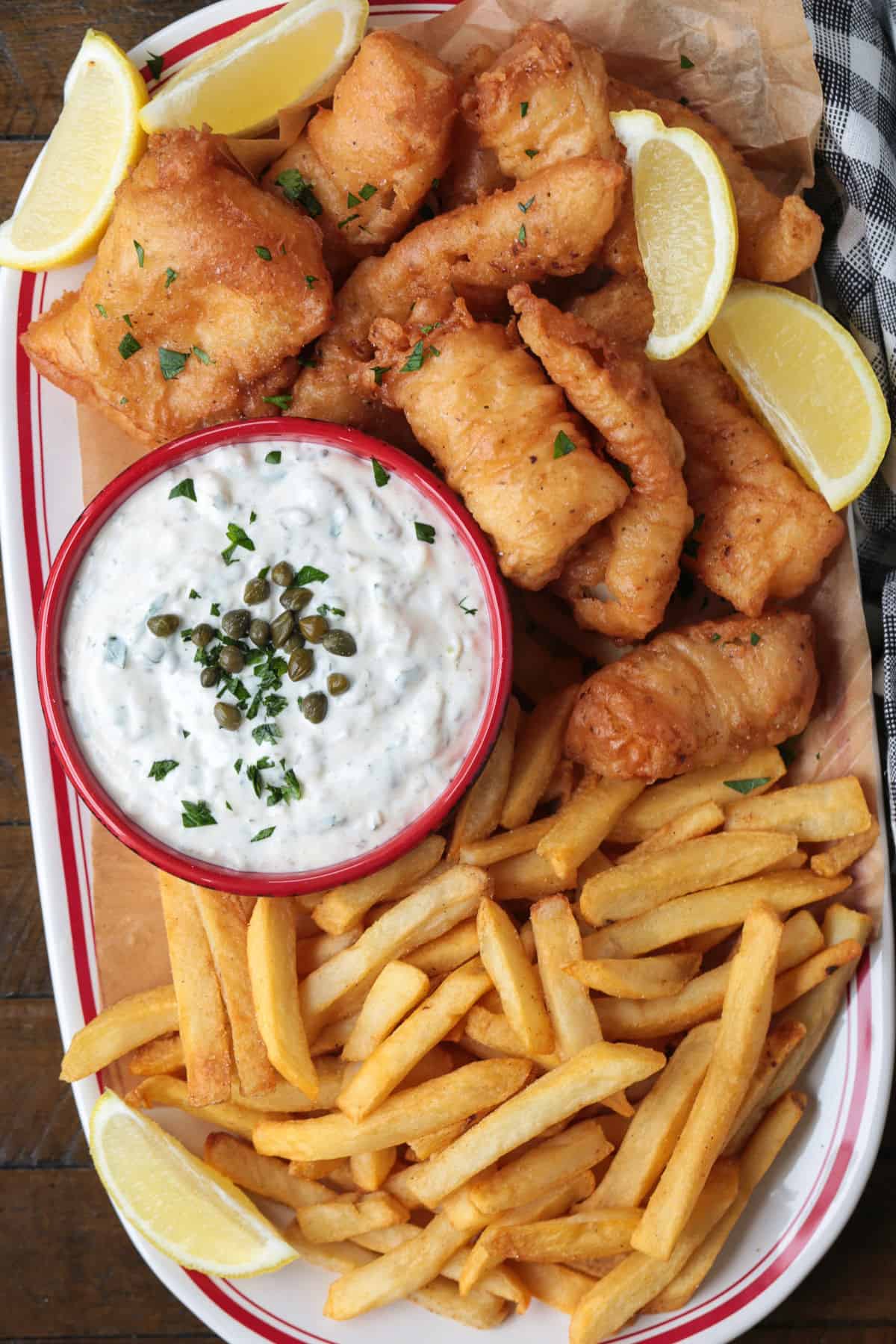Make crispy, golden beer battered cod at home with our easy recipe! Flaky cod coated in a light beer batter and fried to a crispy perfection. fried cod strips on a platter with french fries and tartar sauce