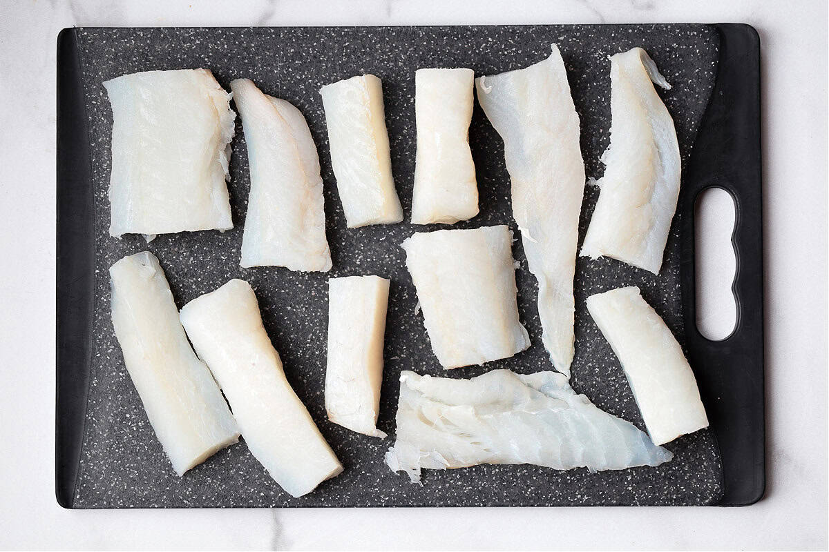 Make crispy, golden beer battered cod at home with our easy recipe! Flaky cod coated in a light beer batter and fried to a crispy perfection. cod cut into pieces on board