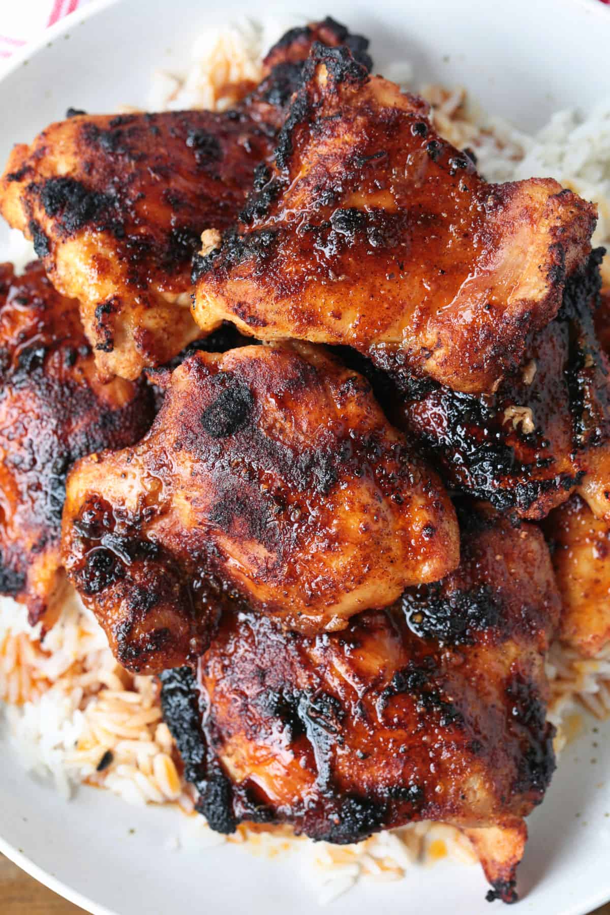 Tender and juicy broiled chicken thighs packed with bold flavor and perfectly caramelized edges. Perfect for meal prepping and easy dinners! broiled chicken thighs with seasonings on plate with rice