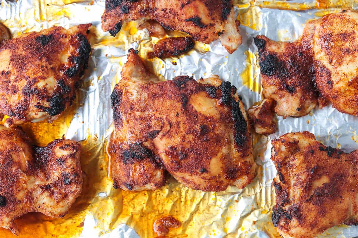 Tender and juicy broiled chicken thighs packed with bold flavor and perfectly caramelized edges. Perfect for meal prepping and easy dinners! broiled chicken on a sheet pan with aluminum foil