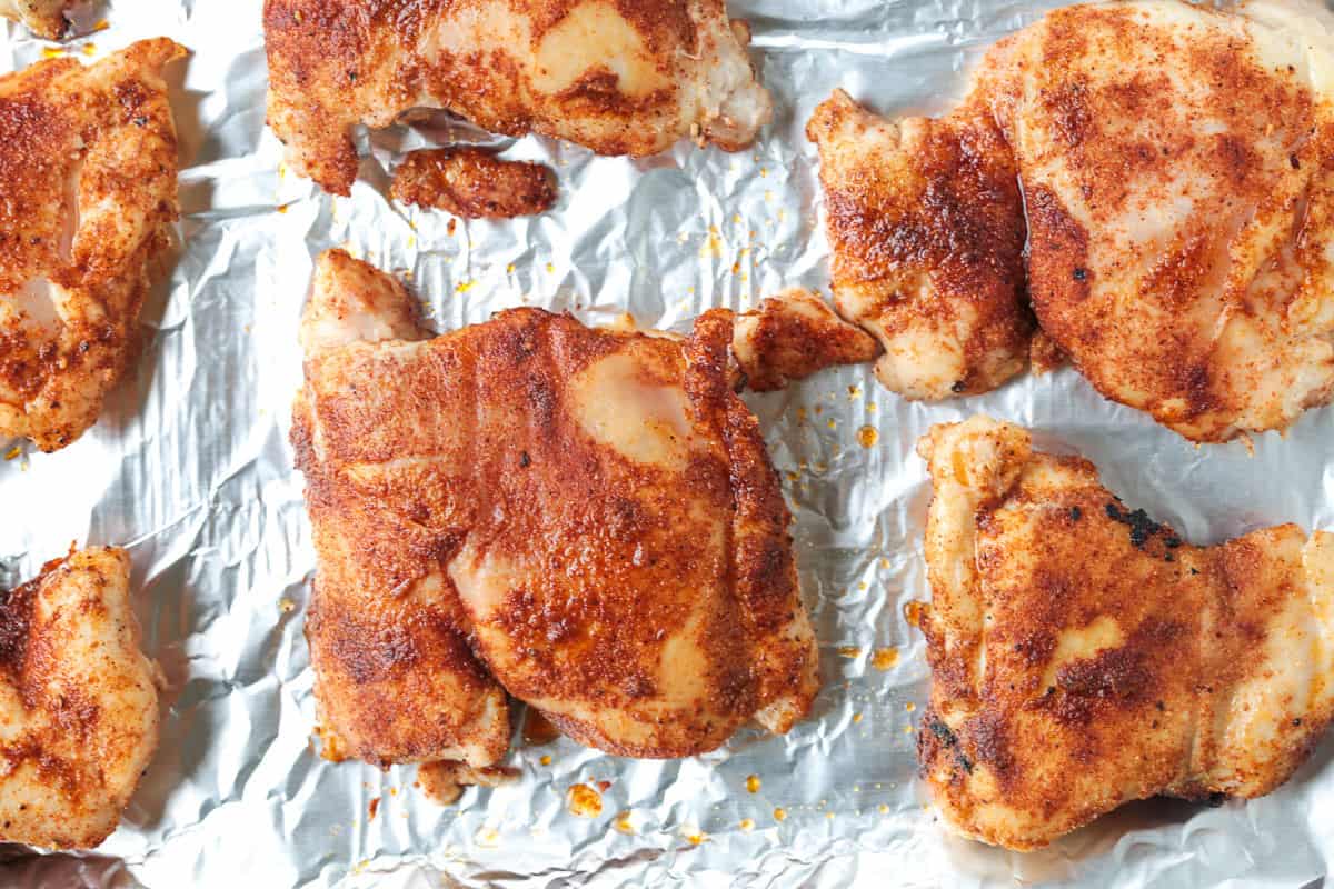 Tender and juicy broiled chicken thighs packed with bold flavor and perfectly caramelized edges. Perfect for meal prepping and easy dinners! chicken thighs on a sheet pan partially cooked