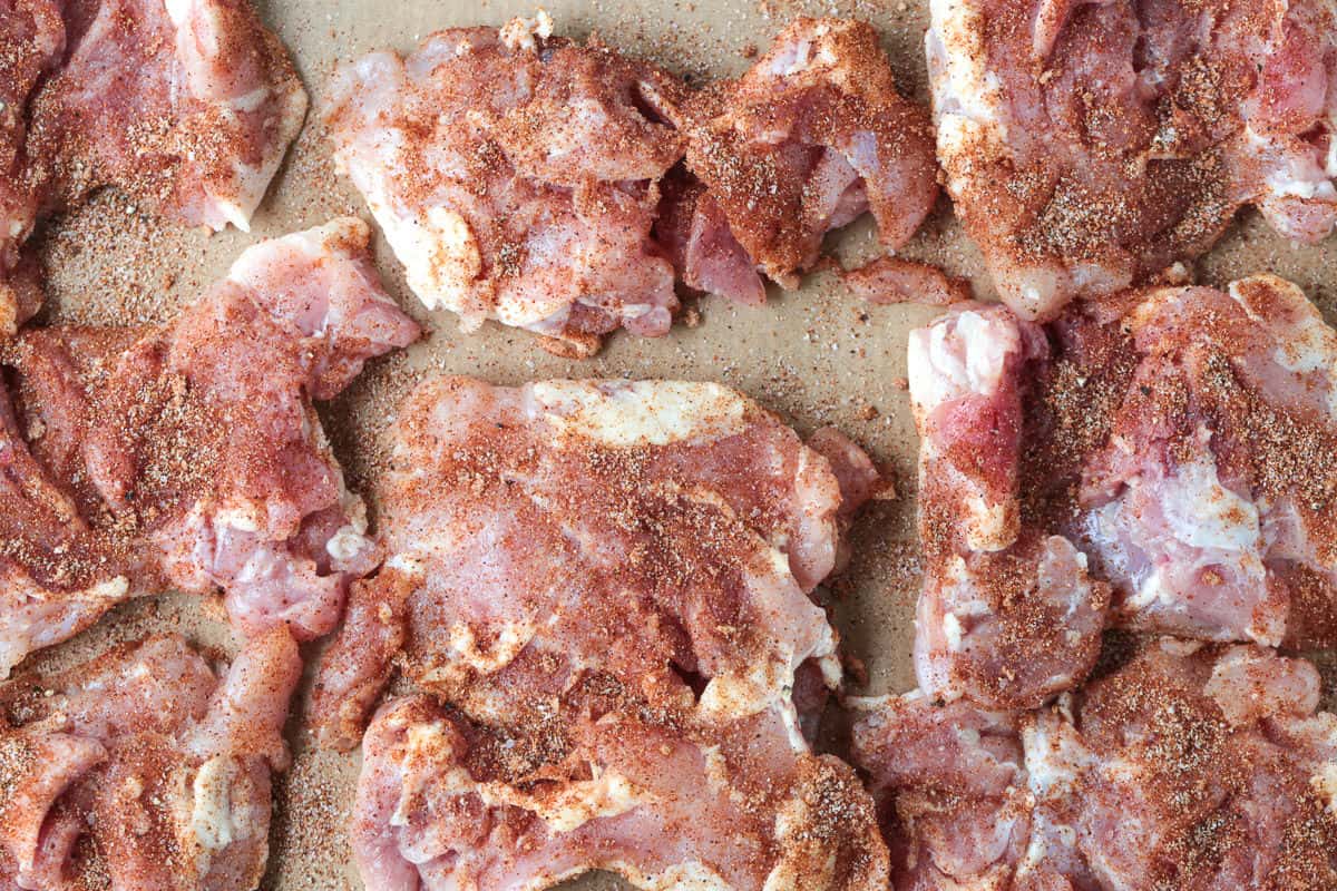 Tender and juicy broiled chicken thighs packed with bold flavor and perfectly caramelized edges. Perfect for meal prepping and easy dinners! raw, seasoned chicken thighs on a sheet pan with aluminum foil