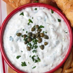 tartar sauce in red bowl with fried fish and french fries