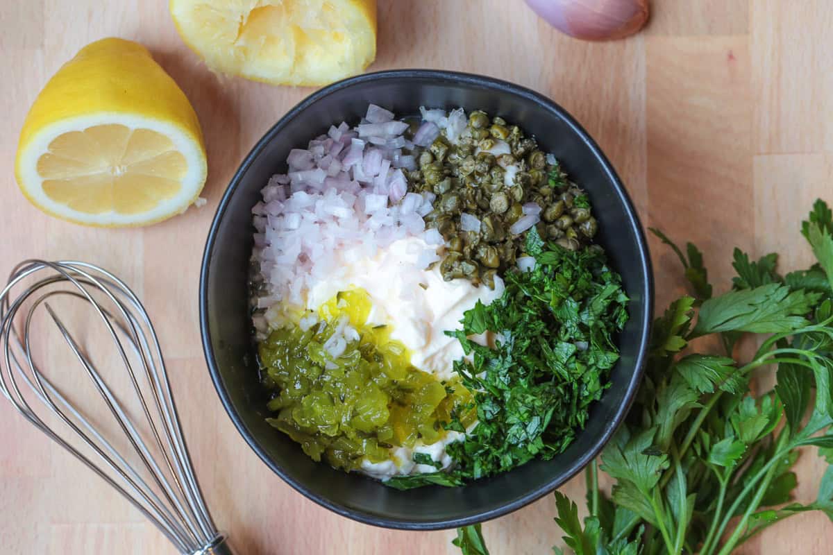 Easy homemade tartar sauce is creamy, tangy, and packed with fresh flavor. Delicious on fish, shrimp, fries, and so munch more! ingredients in a bowl for making homemade tartar sauce