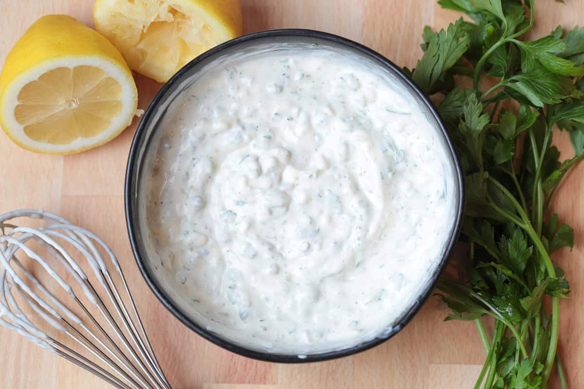 Easy homemade tartar sauce is creamy, tangy, and packed with fresh flavor. Delicious on fish, shrimp, fries, and so munch more! tartar sauce in black bowl with whisk on the side