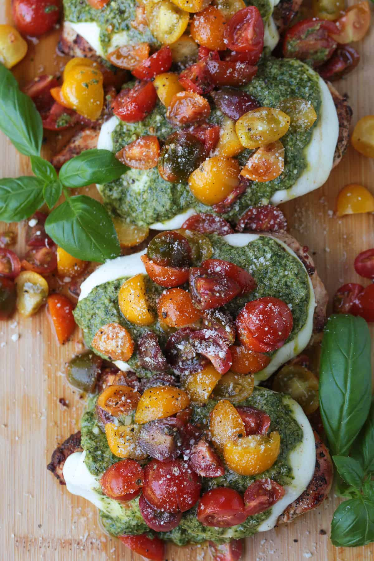 Grilled Chicken Margherita is an easy dinner recipe made with juicy grilled chicken, fresh mozzarella, ripe tomatoes, garlic, and pesto. chicken margherita on a board with basil