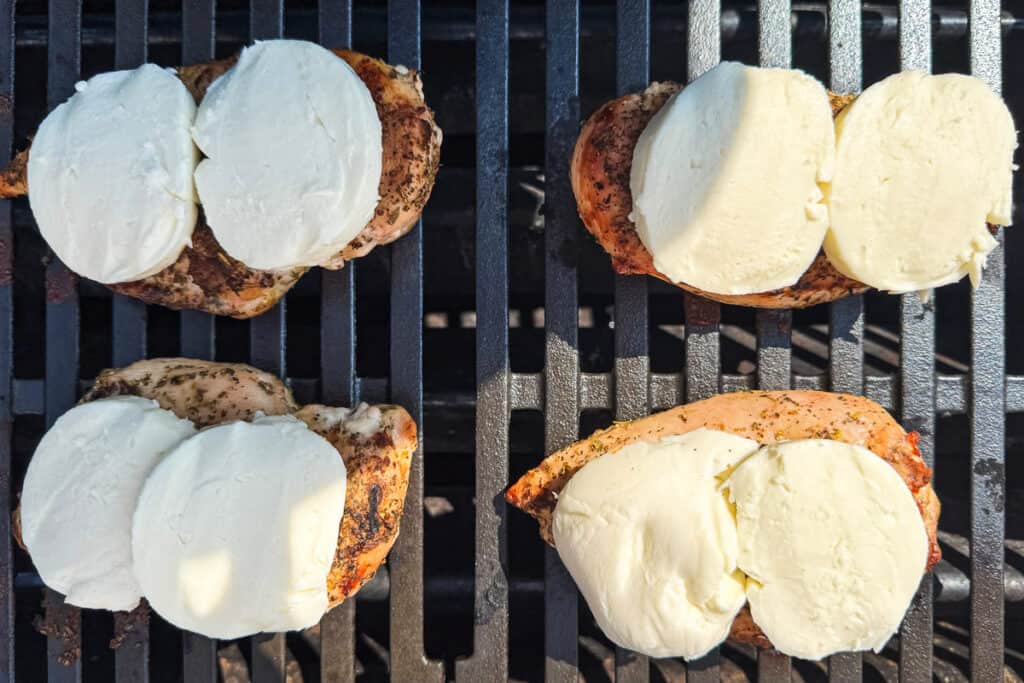 Grilled Chicken Margherita is an easy dinner recipe made with juicy grilled chicken, fresh mozzarella, ripe tomatoes, garlic, and pesto. chicken on the grill with mozzarella cheese